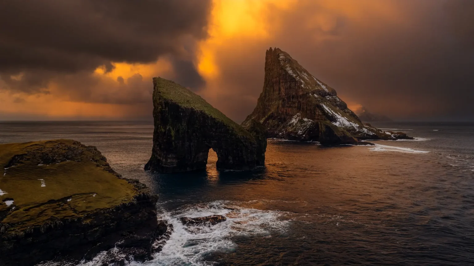Aerial view of Drangarnir sea stacks with ominous clouds at sunrise, Faroe Islands